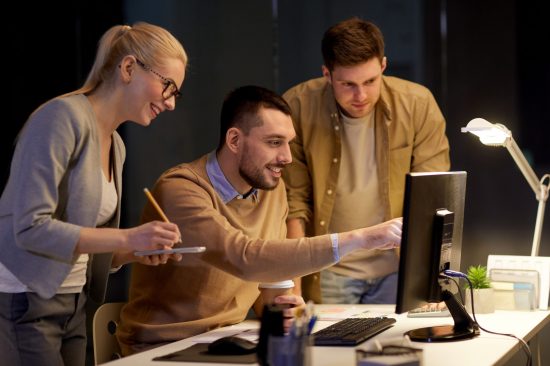 Three engineers working on a project at a computer.