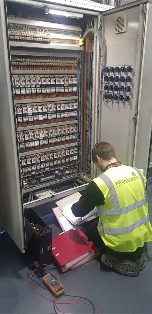 MCI Electronics engineer faultfinding and repairing a PLC control panel.